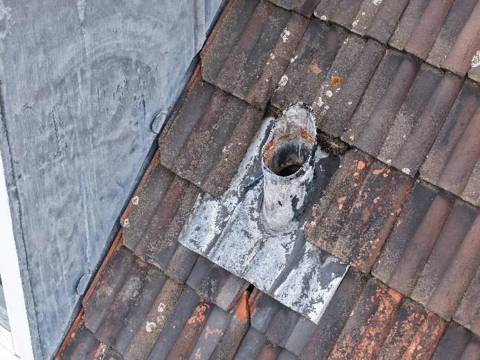 Redundant weathering slate around a vent pipe and missing lead flashing at a dormer cheek
